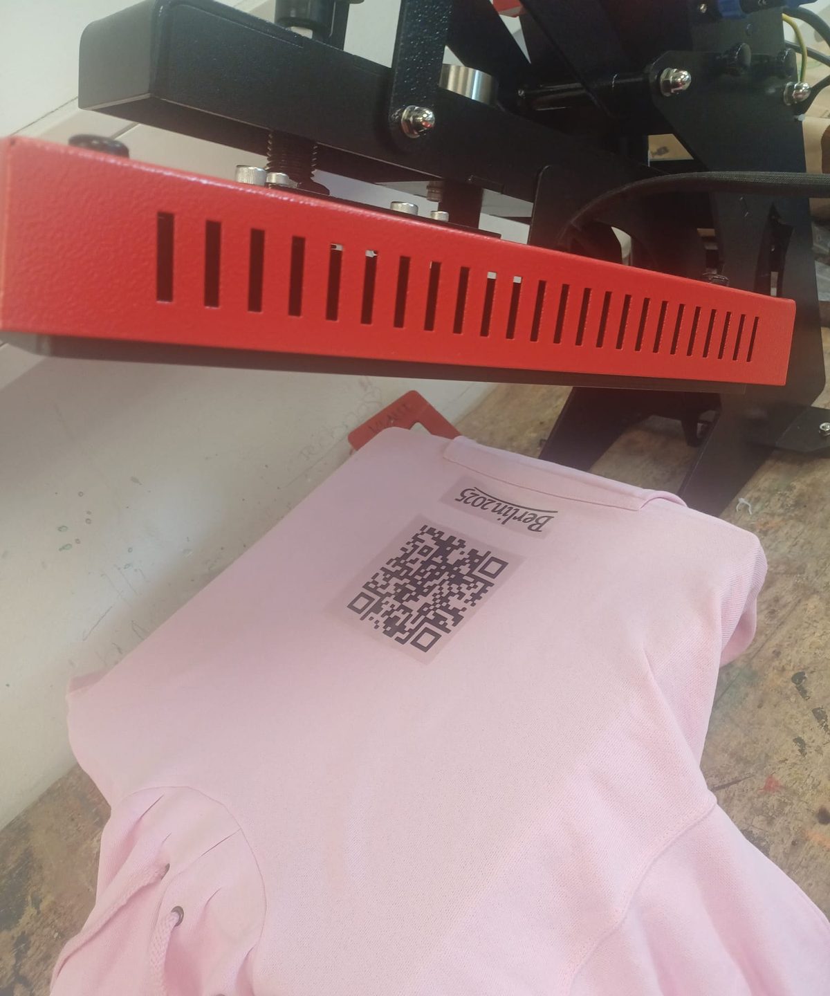 Rosa Hoodie mit aufgepresstem Motiv unter der geöffneten Transferpresse